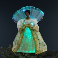 a lighted doll is sitting on top of a christmas tree