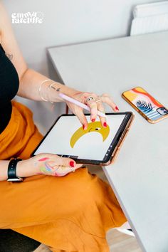 a woman sitting at a table using an ipad with her hand on the screen and holding a pen