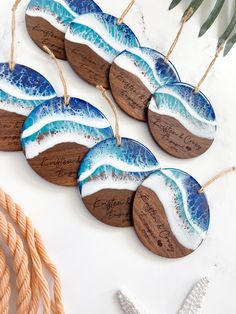 five handmade wooden ornaments with blue and white designs on them next to starfish