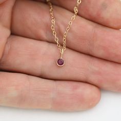 Very classy, simple, and dainty. This handcrafted gold pendant has a natural Ruby stone and comes on your choice of a 16 or an 18 inch gold chain with the artist's tag attached to the clasp. It can also be paired with other pendants! Mix and match to create your own personalized necklace or mother necklace! Gold is 14ky. Stone measures 3mm in diameter. Birthstone for July. Available in A grade or AA grade, please select the stone grade when adding this item to the cart. All Laine Benthall jewelr Yellow Gold Dainty Jewelry, Small Dainty Yellow Gold Jewelry, Dainty Yellow Gold Jewelry, 14k Gold Round Pendant Birthstone Necklace Gift, Minimalist 14k Rose Gold Birthstone Necklace, Minimalist Rose Gold 14k Birthstone Necklace, Minimalist 14k Gold Charm Necklace With May Birthstone, 14k Gold Pendant Birthstone Necklace For Gift, Dainty 14k Gold Hypoallergenic Necklace