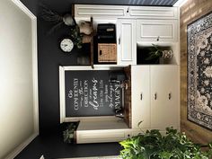 a black and white kitchen with chalkboard on the cupboards, potted plants and rug