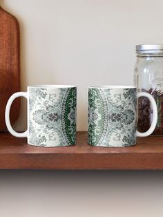 two coffee mugs sitting on top of a wooden shelf