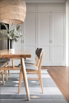 a dining room table and chairs in front of white cupboards