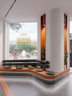 an empty room with benches and plants on the floor near large windows that look out onto a city