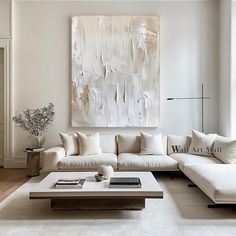 a living room filled with white furniture and a large painting on the wall above it