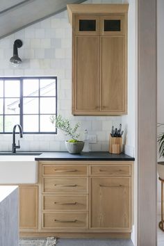 a kitchen with wooden cabinets and black counter tops in front of a large window that looks out onto the outdoors