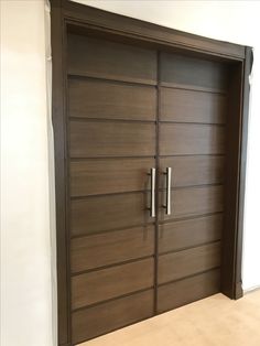 a large wooden door in the corner of a room with white walls and flooring