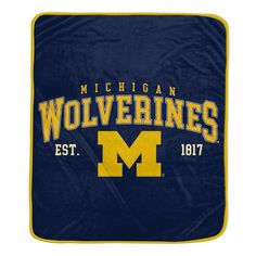 the michigan wolverines blanket is shown in blue and yellow with an embroidered logo on it