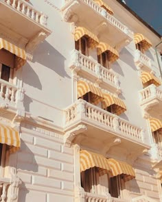 an old building with yellow and white striped awnings on the balconies