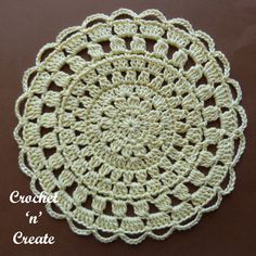 a crocheted doily is shown on a brown surface