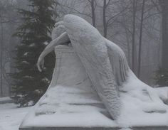 an angel statue is covered in snow near trees