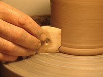 a person making a vase out of clay on a potter's wheel with their hands