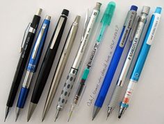 several pens are lined up next to each other on a white surface with writing underneath them