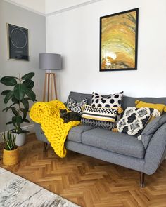 a grey couch with yellow and black pillows