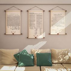 three framed papers hang on the wall above a couch with pillows and throw pillows in front of it