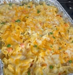 a casserole dish with noodles, peas and cheese in it on aluminum foil