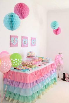 a table topped with lots of colorful balloons and paper lanterns hanging from the ceiling above it