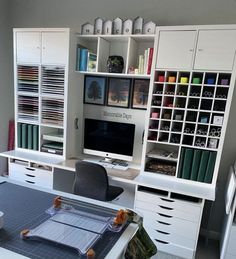 a desk with a computer, bookshelf and many other items on top of it