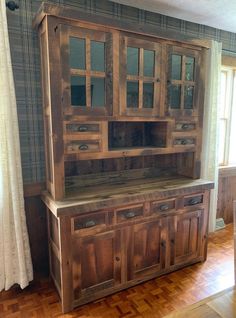 a large wooden cabinet sitting on top of a hard wood floor next to a window