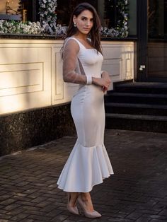 a woman in a white dress standing on the street