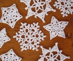 crocheted snowflakes are arranged on a wooden surface, including one in the center