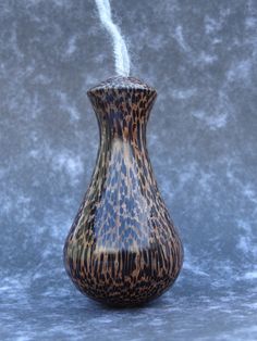 a brown and black vase sitting on top of a blue table next to a gray wall