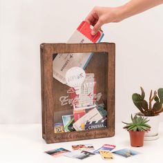 a person holding a red object over a wooden box filled with photos and other items