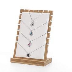 three necklaces are displayed in a wooden display case on a white background with wood stand