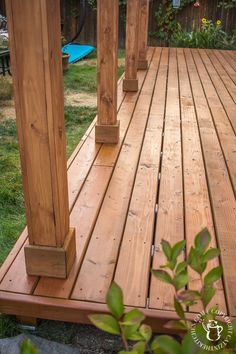 a wooden deck with columns and grass in the background