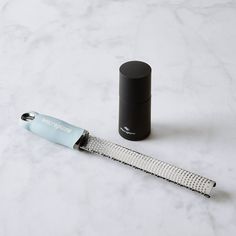 a pen and roller on a white marble counter top next to a black cylindrical container