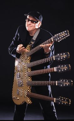 the man is holding six guitars in his hands