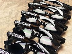 six pairs of sunglasses with the names groomsman and groomsmen on them sitting on a wooden surface