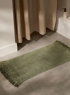 a green rug on the floor next to a bath tub