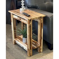 a wooden table with a cell phone on it next to a black leather couch in a living room