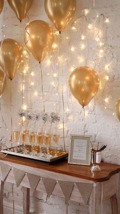 a table topped with lots of balloons and champagne glasses next to a white brick wall