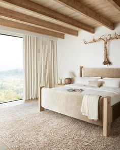 a bedroom with a large bed and wooden beams on the ceiling, along with an open window