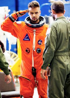 a man in an orange space suit standing next to another man with his hand on his head