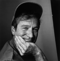 a black and white photo of a man with his hand on his chin looking at the camera