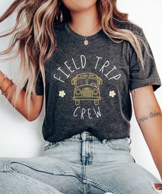 a woman sitting on the ground wearing a t - shirt that says field trip crew