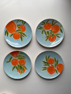 four plates with oranges painted on them