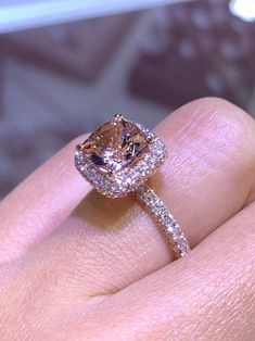 a close up of a person's hand holding an engagement ring with a fancy diamond