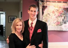 a man and woman standing next to each other in front of a wall with paintings on it