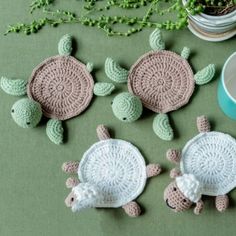 crocheted sea turtle coasters and cups on a green surface with plants in the background