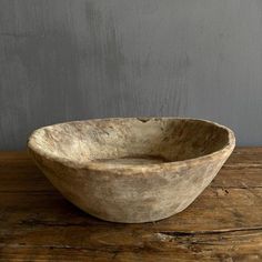 a wooden bowl sitting on top of a wooden table next to a gray painted wall