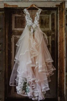 a wedding dress hanging on a door with flowers in the front and bottom tiers