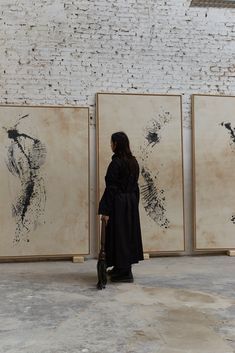 a woman standing in front of three paintings