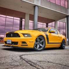 a yellow mustang parked in front of a building