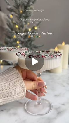 a person holding a wine glass in front of a christmas tree