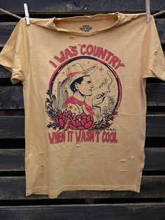 I Was Country When it wasn't Cool unisex distressed T shirt in vintage wash white and Mustard Vintage country western cowboy T shirt 40 Singles Jersey 100% Cotton Premium quality ringspun and compacted cotton Fine Cotton Jersey that is pigment dyed for a more vintage look Features tears and destroyed features at neck and on body Each piece is unique as this process is done by hand! 3.8 oz Made In USA Every garment dye item can be a slightly different shade in color since this is a laundry dye pr Retro T-shirt For Summer Country Concerts, Vintage Washed T-shirt For Spring, Vintage Summer T-shirt For Rodeo, Vintage Faded T-shirt Pre-washed, Western Style T-shirt For Ranch In Summer, Western Pre-shrunk Tops For Summer, Western Style Summer T-shirt, Vintage Acid Wash Pre-washed T-shirt, Faded Distressed T-shirt For Summer