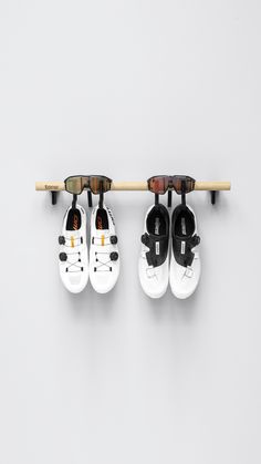 three pairs of shoes hanging on a wall with sunglasses attached to the pegs above them